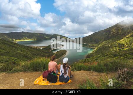 Vista posteriore di due amici in cima alla collina contro splendido paesaggio estivo con foresta e lago in estate. Turisti che ammirano la natura meravigliosa delle Azzorre Foto Stock