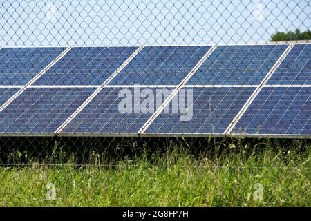 Array fotovoltaico nell'Open Behind A Chain-link Fence. Immagine iconica , meno promozione delle energie rinnovabili, Politica Foto Stock
