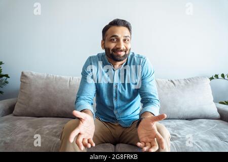 Bel giovane indiano che parla con la macchina fotografica che si sente indiziato confusa gesturing Foto Stock