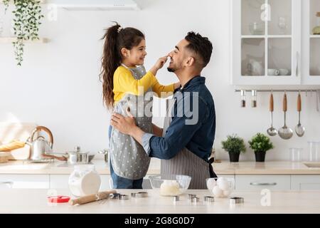 Felice papà medio-orientale e piccola figlia che si divertano mentre si cuoce in cucina Foto Stock