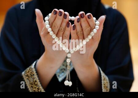 Primo piano delle mani di una donna musulmana in abaya mentre teneva il rosario e pregava, Emirati Arabi Uniti, Medio Oriente Foto Stock