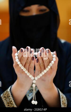 Primo piano delle mani di una donna musulmana in abaya mentre teneva il rosario e pregava, Emirati Arabi Uniti, Medio Oriente Foto Stock