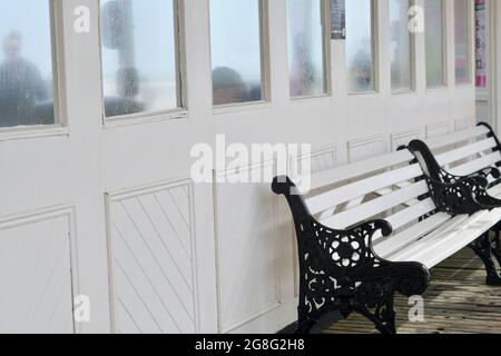 La lunga passerella in legno del Victorian Palace Pier presenta aree salotto con pannelli in legno che proteggono il pubblico da condizioni atmosferiche avverse e venti Foto Stock