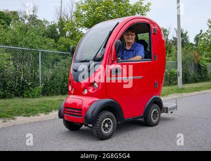 Uomo anziano che guida uno scooter completamente chiuso tutto il tempo utilità su un percorso a Ottawa, Canada Foto Stock