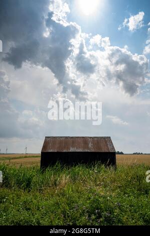 Tick Fen Warboys, Cambridgeshire, Regno Unito. 20 luglio 2021. Le nubi della tempesta si radunano nel grande cielo angliano orientale sopra un fienile nelle Fens Cambridgeshire. L'ondata di caldo e il clima umido hanno creato temporali in tutta l'est del Regno Unito. Per il resto della settimana si prevedono temperature elevate continue. Credit: Julian Eales/Alamy Live News Foto Stock