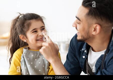 Divertimento di cottura. Piccola ragazza e il suo papà arabo che si fooling insieme in cucina Foto Stock