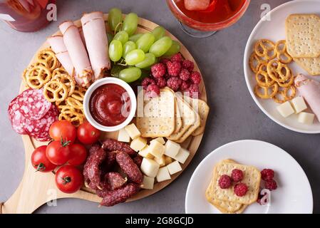 Una tavola rotonda di salumi con salsiccia, formaggio, cracker e frutta, piatti con antipasto, primo piano. Foto Stock