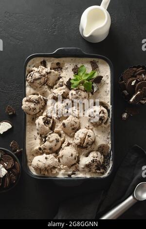 Gelato cremoso con biscotti al cioccolato in contenitore nero. Vista dall'alto. Formato verticale. Foto Stock