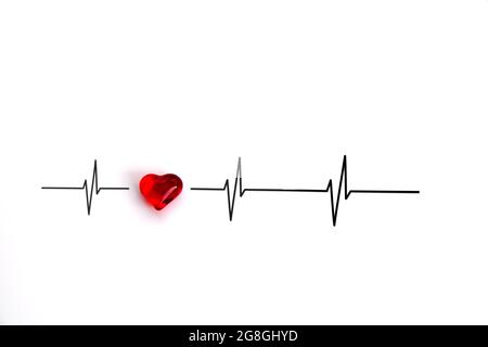 Cuore di vetro rosso riflettente la luce con curve di cicli cardiaci o battiti cardiaci in un elettrocardiogramma (ECG) su sfondo bianco Foto Stock