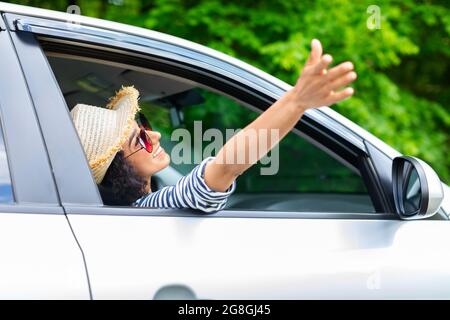 Giovane donna gioiosa che si rilassa mentre si va in auto Foto Stock