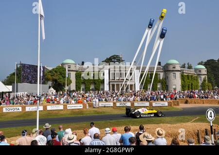 Auto da corsa Renault RE40 che corre la salita al Goodwood Festival of Speed Event, nel Regno Unito, passando Goodwood House e la Porsche Central Feature Foto Stock