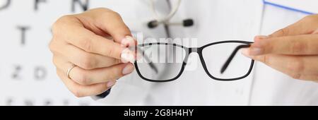 Le mani del dottore womans tengono i nuovi occhiali in ottica Foto Stock