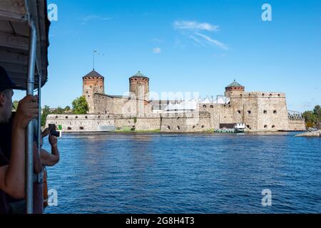 I turisti in crociera sul lago Saimaa scattano foto della fortezza medievale in pietra di Olavinlinna, sede del Festival dell'Opera di Savonlinna, a Savonlinna, Finlandia Foto Stock