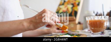 L'artista femminile mescola vernice a pennello su tavolozza Foto Stock