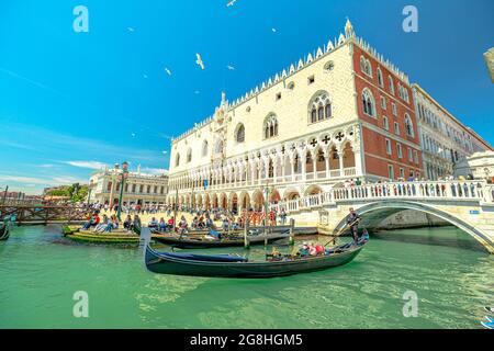 Venezia, Italia - 9 maggio 2021: Gondole tradizionali per la crociera turistica sul canale della Giudecca in Piazza San Marco con il Palazzo Ducale. Il principale e più grande Foto Stock