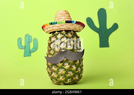 Divertente ananas in sombrero e baffi di carta su sfondo a colori Foto Stock