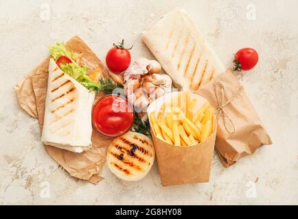 Gustosi kebab doner, salsa e patatine fritte su sfondo chiaro Foto Stock