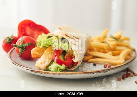 Piatto con gustoso doner kebab e patatine fritte su sfondo chiaro, primo piano Foto Stock