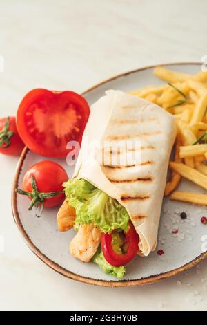 Piatto con gustoso doner kebab e patatine fritte su sfondo chiaro, primo piano Foto Stock