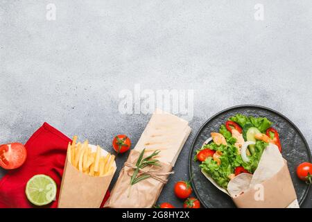 Composizione con gustosi kebab doner e patatine fritte su sfondo chiaro Foto Stock