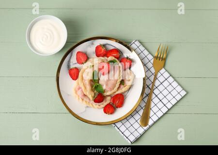 Piatto con gustosi gnocchi di fragola e salsa su sfondo di legno colorato Foto Stock