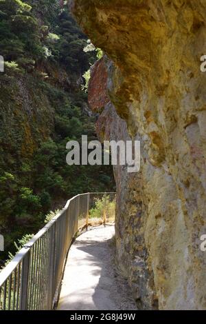 Sentiero stretto con ringhiera in acciaio lungo la parete verticale della roccia con l'altro lato della gola sullo sfondo. Foto Stock