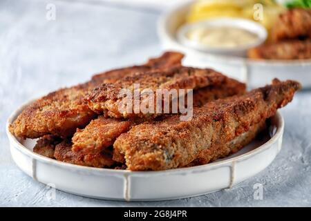 Pesce fritto con piselli verdi, limone e patate fritte Foto Stock