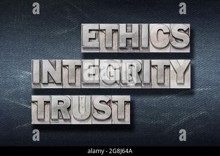 etica, integrità, parole di fiducia realizzate con una stampa di lettere metallizzata su sfondo di jeans scuri Foto Stock