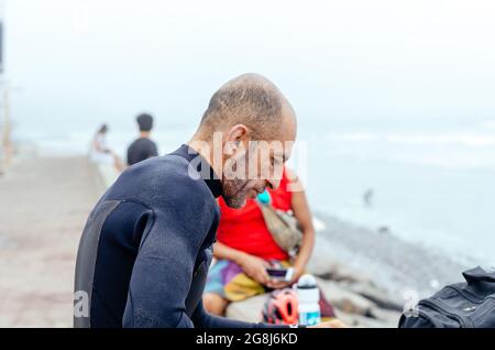 Ritratto di surfista maturo in piedi sulla spiaggia. Foto Stock