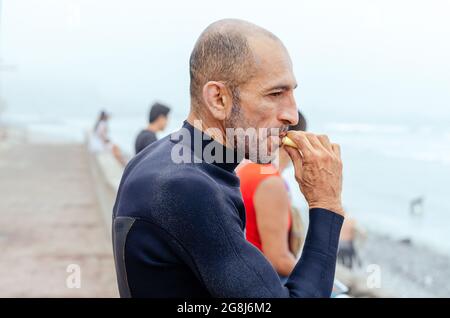 Ritratto di surfista maturo in piedi sulla spiaggia. Foto Stock