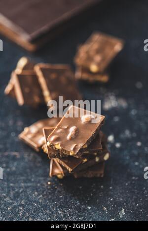 Barretta di cioccolato con noci sul tavolo nero. Foto Stock