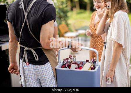 Amici con frigo pieno di alcol durante la festa all'aperto Foto Stock