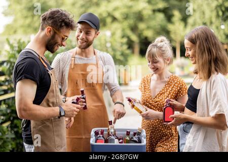 Amici con frigo pieno di alcol durante la festa all'aperto Foto Stock