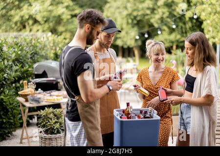 Amici con frigo pieno di alcol durante la festa all'aperto Foto Stock