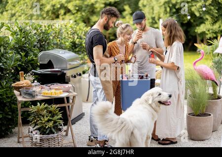 Amici con frigo pieno di alcol durante la festa all'aperto Foto Stock