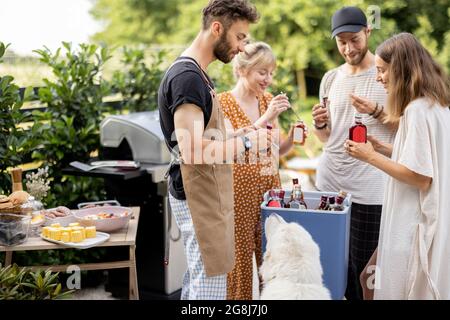 Amici con frigo pieno di alcol durante la festa all'aperto Foto Stock