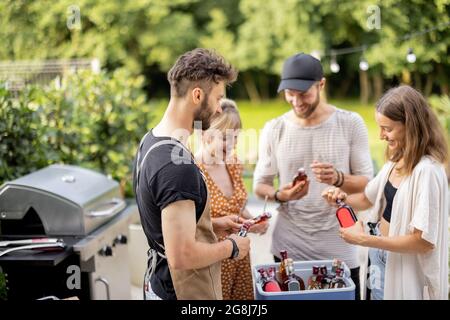 Amici con frigo pieno di alcol durante la festa all'aperto Foto Stock