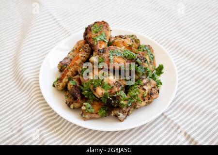 Ali di pollo al parmigiano di aglio fatte in casa su un piatto bianco, vista ad angolo basso. Foto Stock