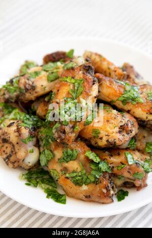 Ali di pollo al parmigiano di aglio fatte in casa su un piatto bianco, vista laterale. Primo piano. Foto Stock