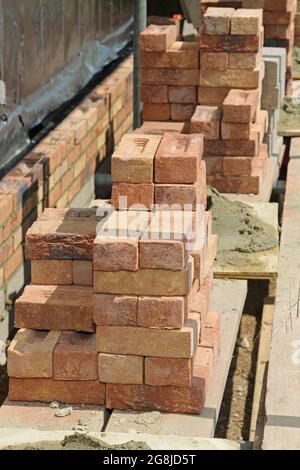 Mattoni accatastati su ponteggi durante la costruzione della parete esterna di un nuovo bungalow a Surrey, Regno Unito Foto Stock