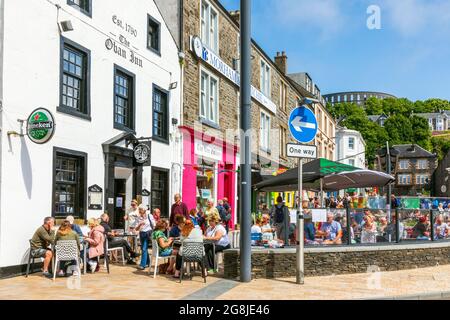 Turisti e patroni che mangiano e bevono all'aperto all'Oban Inn, George Street, Oban vicino a Battery Hill e McCaigs Folly, Oban, Argyll, Scozia, U. Foto Stock