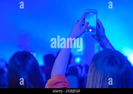 Video di registrazione di musica dal vivo da parte di un adolescente con smartphone - vista posteriore Foto Stock