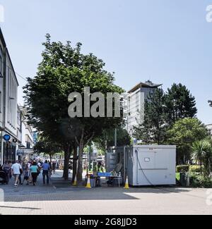 Strada Armada di Plymouth nel centro della città. Gli acquirenti impegnati stanno andando per il loro giorno. Un centro Covid in attesa di visitatori. Clienti che ritornano a metà luglio 2021. Tre Foto Stock