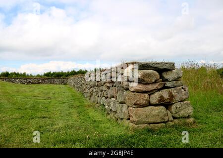 Muro costruito di massi e di erba al campo di battaglia di Culloden in Scozia Foto Stock