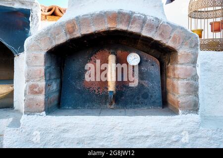 Forno in pietra con porta chiusa in metallo arrugginito e termometro termico Foto Stock