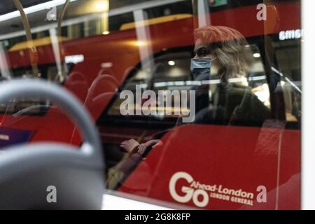 Ragazza bionda che indossa la maschera facciale riflessa nella finestra degli autobus di notte, Londra, 21 febbraio 2021 Foto Stock