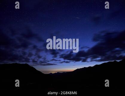 Silhouette di montagne di notte cielo nuvoloso con stelle Foto Stock