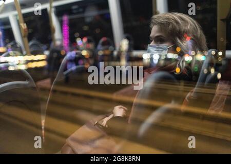 Ragazza bionda che indossa la maschera facciale riflessa nella finestra degli autobus di notte, Londra, 21 febbraio 2021 Foto Stock