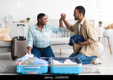 Gioiosa coppia afroamericana valigia impaccata mani a casa Foto Stock