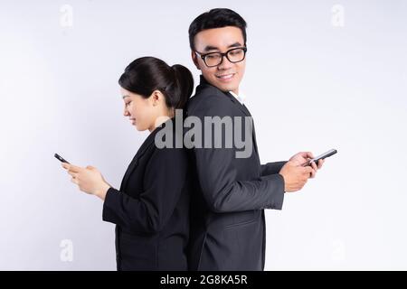 Giovani dipendenti vietnamiti in tute in piedi indietro e l'invio di SMS con i telefoni Foto Stock